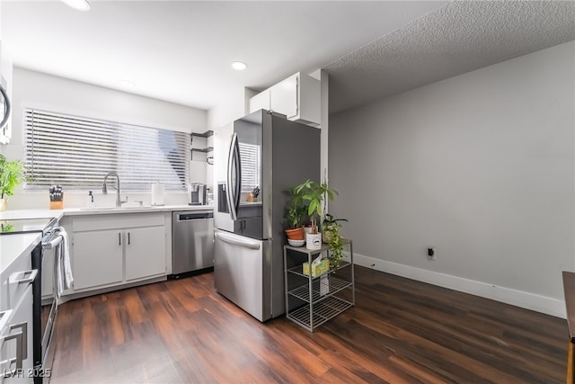 kitchen with sink, appliances with stainless steel finishes, white cabinetry, a textured ceiling, and dark hardwood / wood-style flooring