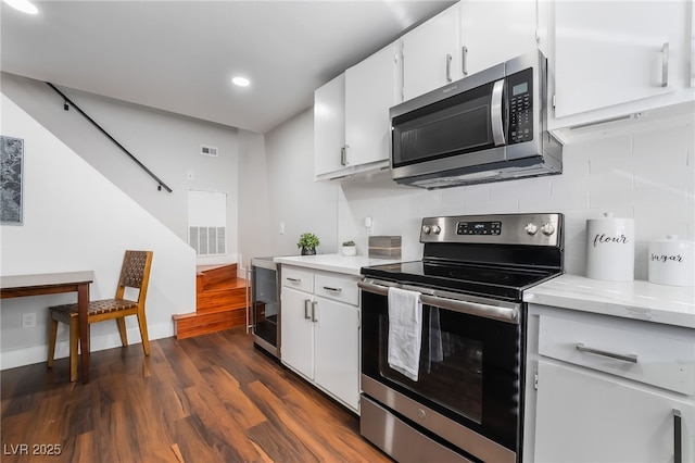 kitchen featuring tasteful backsplash, stainless steel appliances, dark hardwood / wood-style floors, and white cabinets