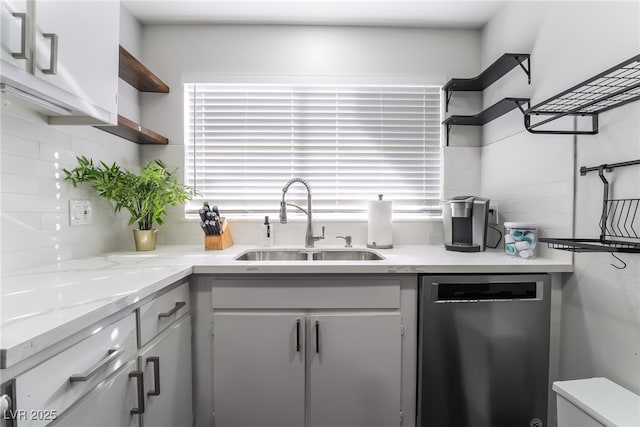 kitchen with sink, white cabinetry, light stone counters, decorative backsplash, and stainless steel dishwasher