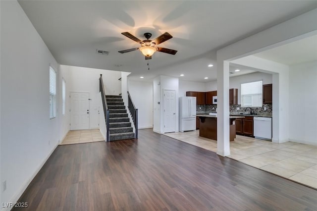 unfurnished living room featuring ceiling fan, sink, and light wood-type flooring