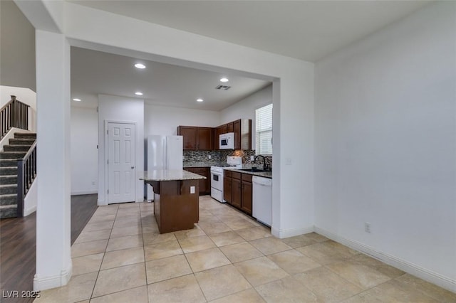 kitchen featuring a breakfast bar, sink, a kitchen island, white appliances, and decorative backsplash