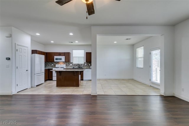 kitchen featuring white appliances, light wood-type flooring, a wealth of natural light, and a kitchen island