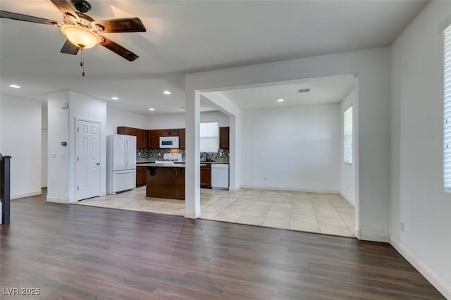 kitchen with decorative backsplash, a center island, ceiling fan, light hardwood / wood-style floors, and white appliances