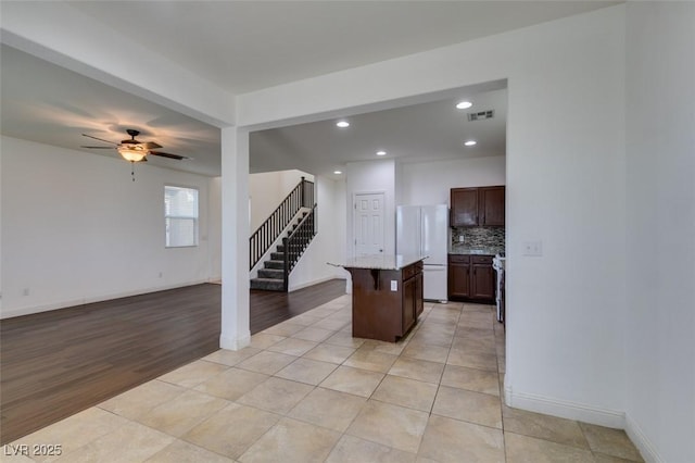 kitchen with light tile patterned floors, backsplash, a kitchen breakfast bar, a kitchen island, and white fridge