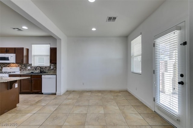 kitchen with light tile patterned flooring, sink, backsplash, a healthy amount of sunlight, and white appliances