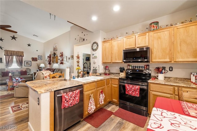 kitchen featuring lofted ceiling, sink, light wood-type flooring, kitchen peninsula, and stainless steel appliances