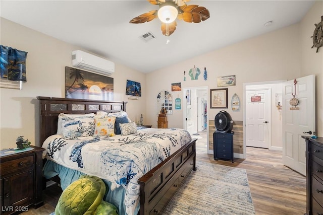 bedroom featuring light hardwood / wood-style flooring, an AC wall unit, and ceiling fan