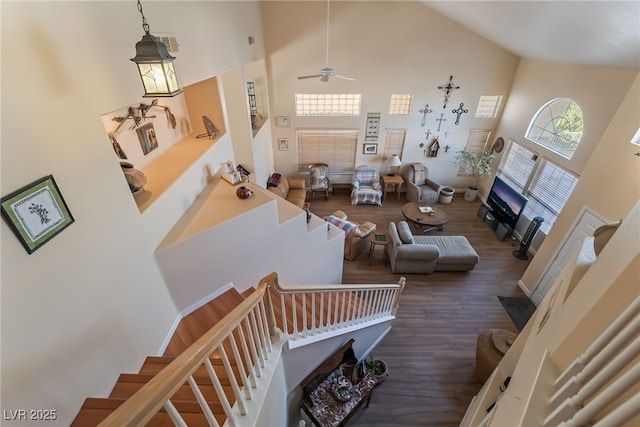 stairway with ceiling fan, wood-type flooring, and high vaulted ceiling