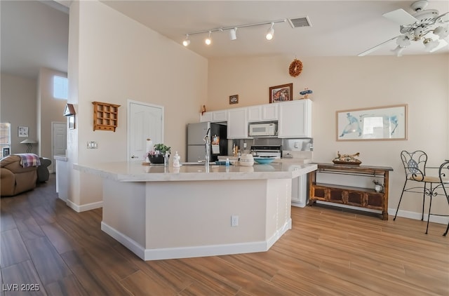 kitchen featuring a kitchen island, stainless steel refrigerator, white cabinets, and range