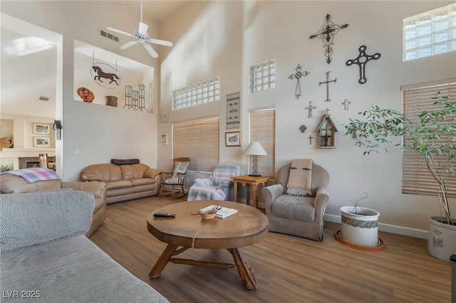 living room with a high ceiling, wood-type flooring, plenty of natural light, and ceiling fan