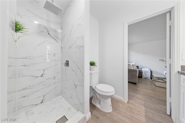 bathroom featuring a tile shower, vanity, wood-type flooring, and toilet