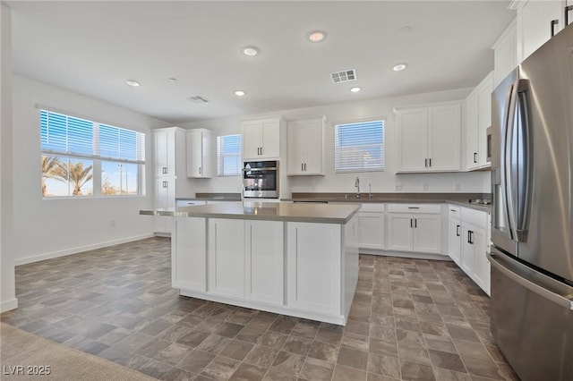 kitchen with stainless steel appliances, a kitchen island, sink, and white cabinets