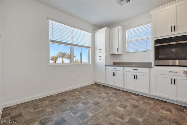 kitchen featuring white cabinets, a wealth of natural light, and oven