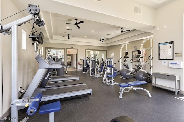 workout area with a raised ceiling and ceiling fan