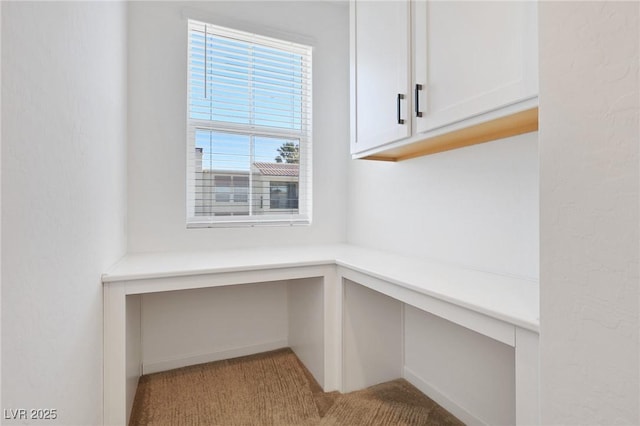 unfurnished office with built in desk and light colored carpet