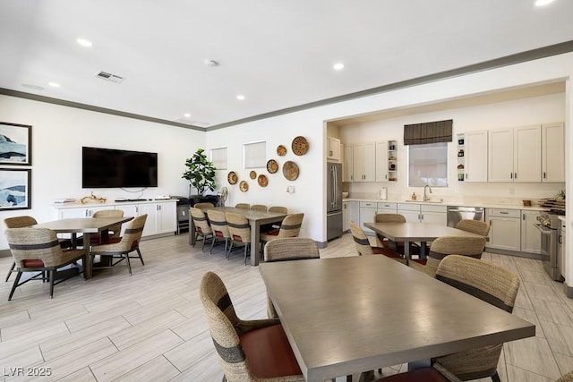 dining space with crown molding and sink