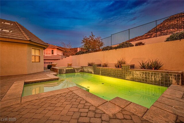 pool at dusk with a patio area