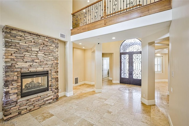 foyer featuring french doors, a fireplace, and a high ceiling