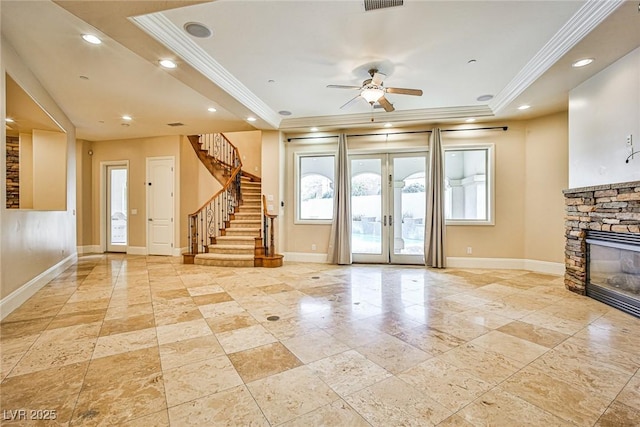 unfurnished living room featuring french doors, a fireplace, ornamental molding, and a tray ceiling