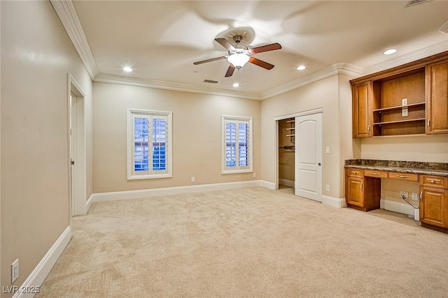 interior space with crown molding, built in desk, light colored carpet, and ceiling fan