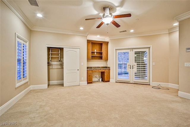 unfurnished living room featuring crown molding, built in desk, light colored carpet, and ceiling fan