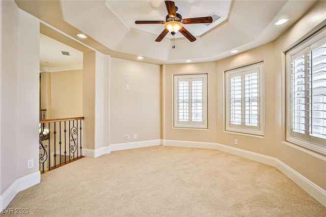 empty room featuring ceiling fan, a tray ceiling, light carpet, and a wealth of natural light