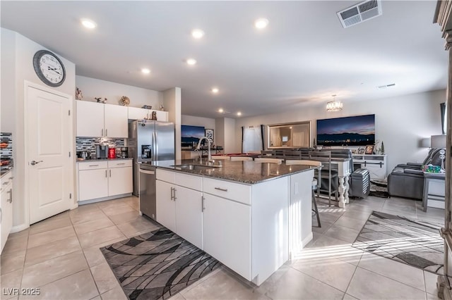 kitchen with an island with sink, a breakfast bar, sink, and white cabinets