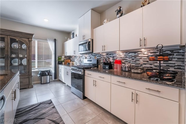 kitchen featuring stainless steel appliances, white cabinetry, dark stone countertops, and light tile patterned flooring