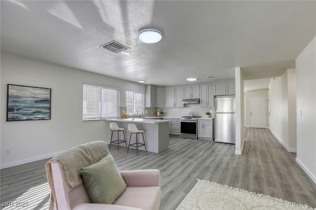 kitchen featuring sink, gray cabinets, appliances with stainless steel finishes, a kitchen breakfast bar, and kitchen peninsula