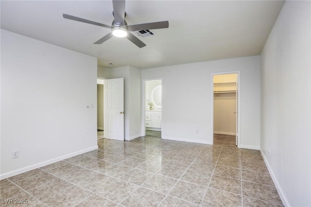 unfurnished bedroom featuring ensuite bath, a spacious closet, ceiling fan, and a closet