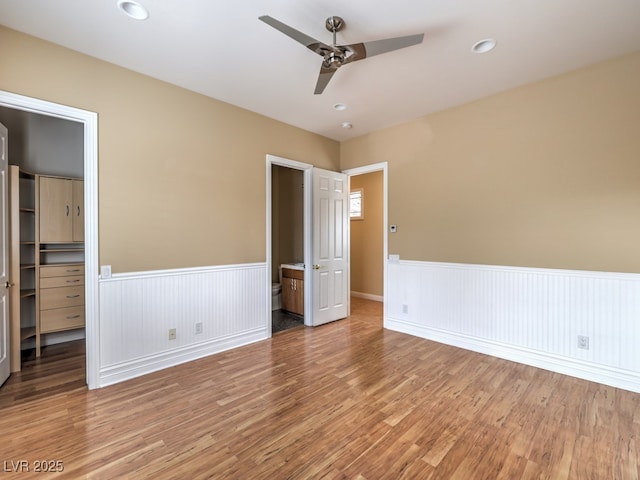 3 Pine Hollow Dr, Henderson, NV 89052 - unfurnished bedroom featuring a spacious closet, wainscoting, light wood-style flooring, a closet, and a ceiling fan