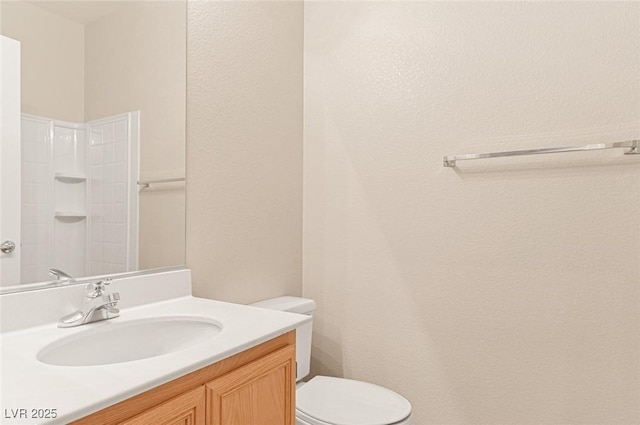 bathroom featuring walk in shower, vanity, and toilet