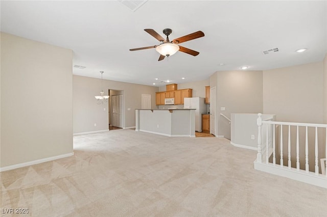 unfurnished living room with ceiling fan with notable chandelier and light colored carpet