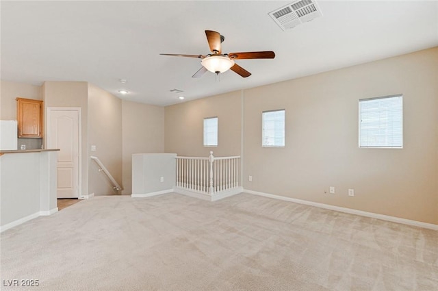 empty room with ceiling fan and light carpet