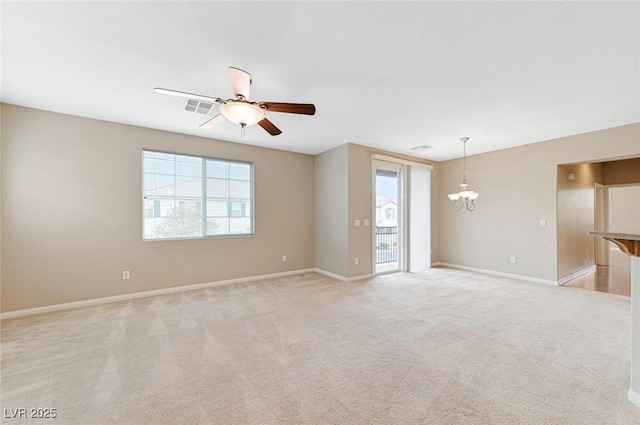 carpeted spare room with ceiling fan with notable chandelier