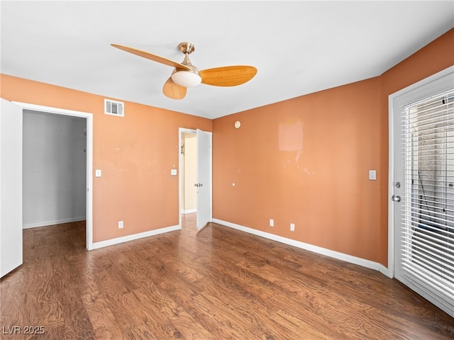 interior space featuring a ceiling fan, visible vents, baseboards, and wood finished floors