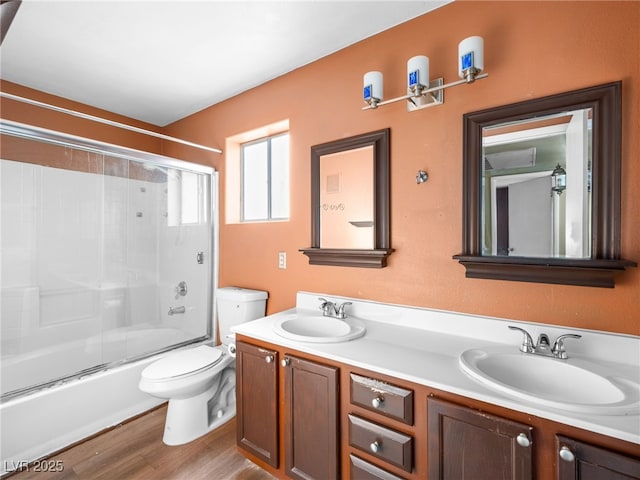 bathroom with wood finished floors, a sink, toilet, and double vanity