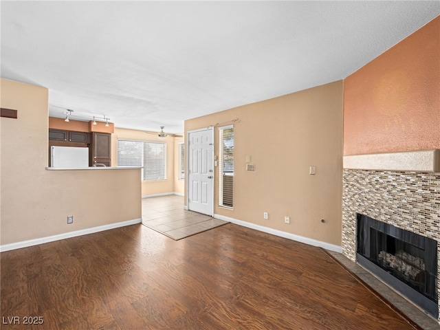 unfurnished living room featuring a fireplace, wood finished floors, and baseboards