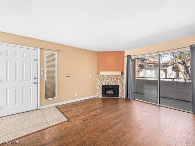 unfurnished living room with baseboards, wood finished floors, and a tile fireplace