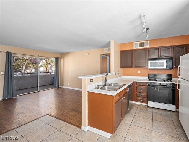 kitchen featuring visible vents, dishwasher, range with gas cooktop, freestanding refrigerator, and a peninsula