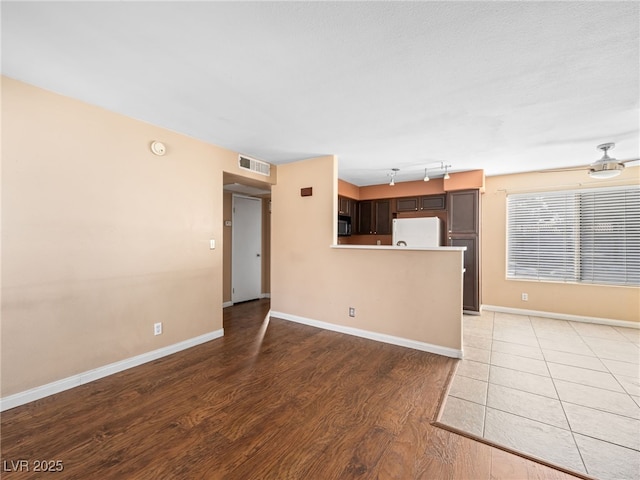 unfurnished living room featuring baseboards, ceiling fan, visible vents, and light wood-style floors