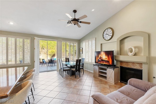 interior space featuring a tile fireplace, vaulted ceiling, and ceiling fan