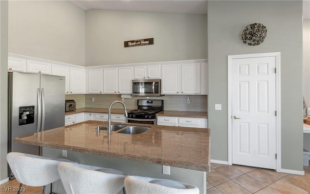 kitchen featuring sink, appliances with stainless steel finishes, white cabinetry, high vaulted ceiling, and tasteful backsplash