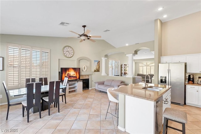 kitchen featuring lofted ceiling, sink, a breakfast bar, appliances with stainless steel finishes, and a kitchen island with sink