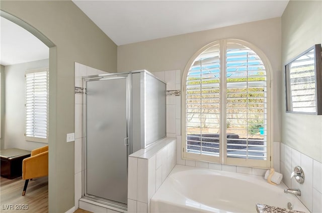 bathroom with wood-type flooring and shower with separate bathtub