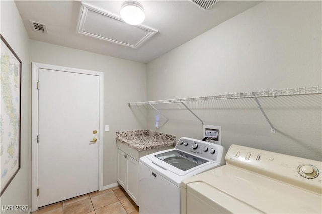 washroom with cabinets, washer and dryer, and light tile patterned floors