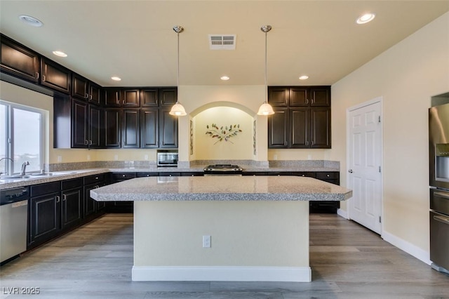 kitchen with pendant lighting, appliances with stainless steel finishes, a center island, and sink