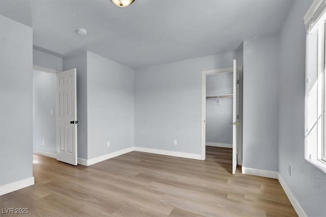 unfurnished bedroom featuring multiple windows, light hardwood / wood-style floors, and a closet