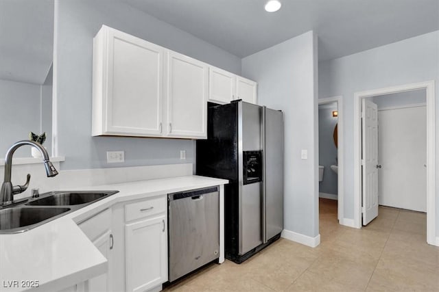 kitchen with stainless steel appliances, sink, light tile patterned floors, and white cabinets