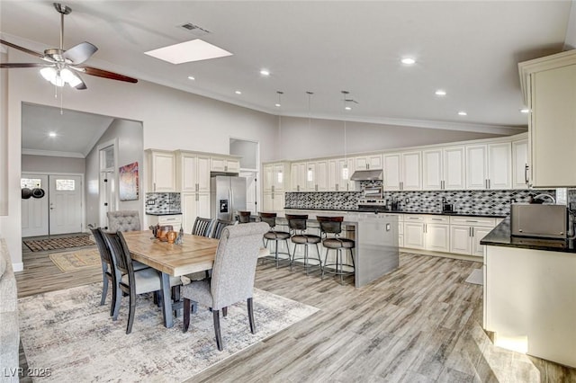 dining space featuring crown molding, ceiling fan, high vaulted ceiling, and light hardwood / wood-style floors